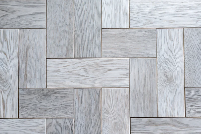 Close-up of light grey whitewashed oak parquet floor arranged in herringbone pattern