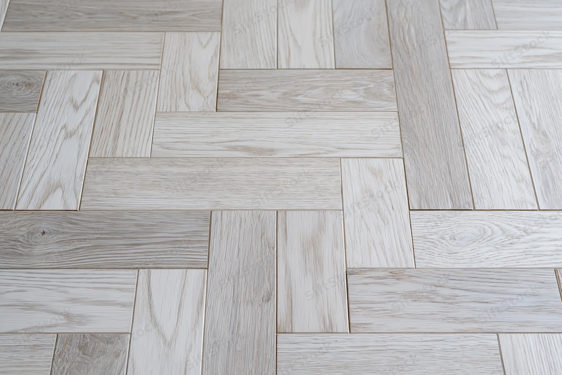 Close-up of light grey whitewashed oak parquet floor arranged in herringbone pattern