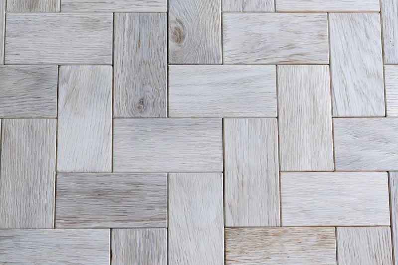 Close-up of light grey whitewashed oak parquet floor arranged in herringbone pattern