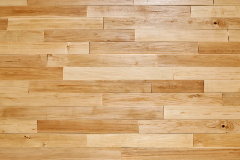 Light hardwood parquet flooring arranged in staggered planks filling the frame