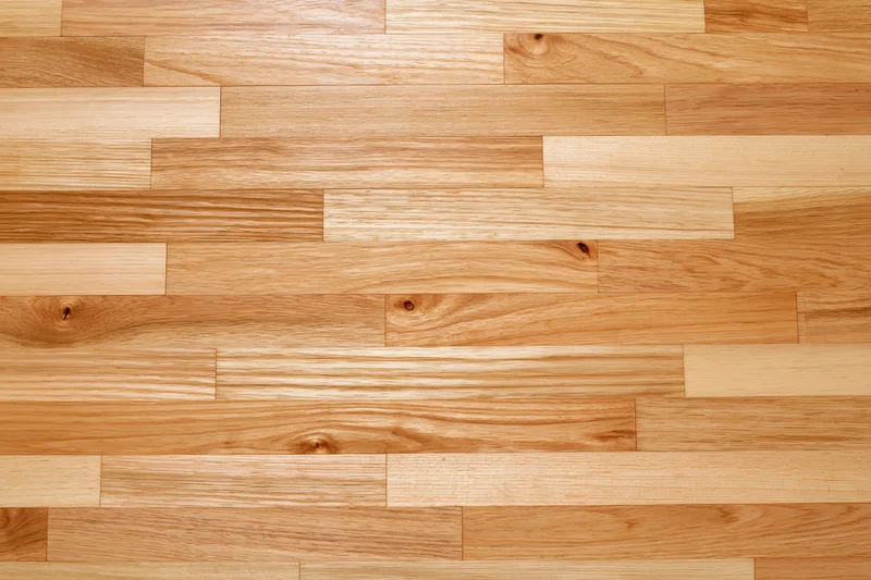 Light hardwood parquet flooring arranged in staggered planks filling the frame