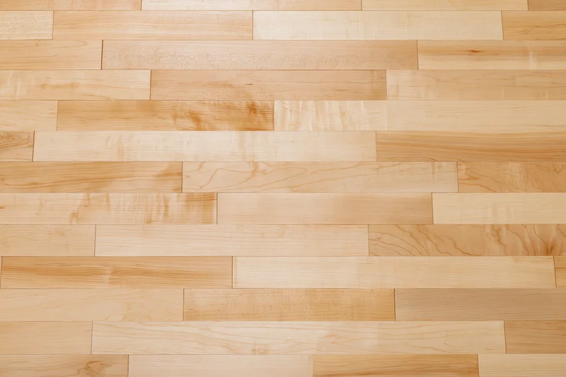 Close-up flat lay of light maple hardwood floor planks arranged in horizontal rows with visible wood grain and natural texture