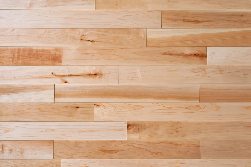Light maple hardwood flooring planks arranged in staggered pattern for interior flooring