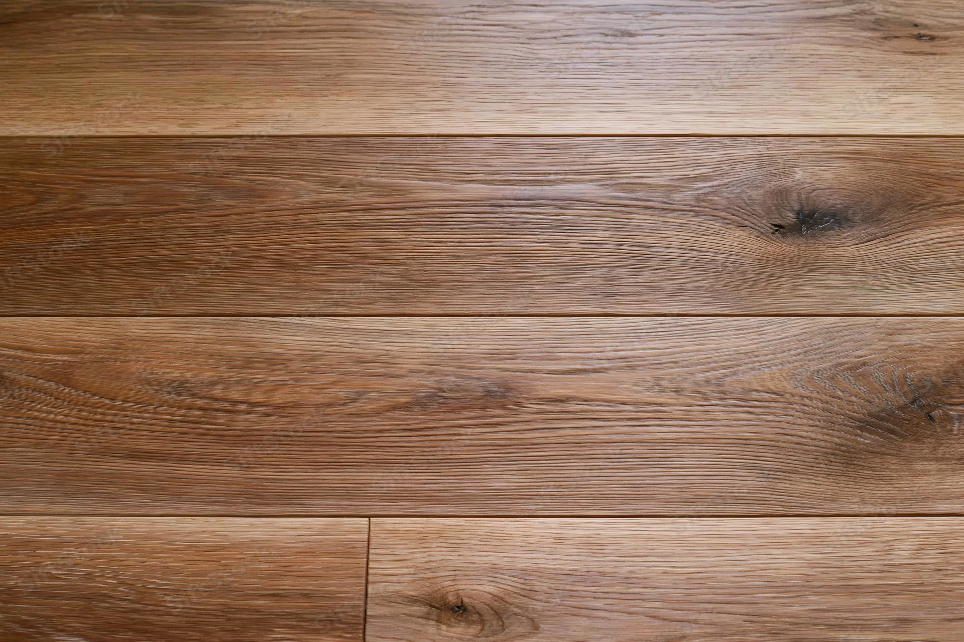 Close-up of medium brown oak hardwood flooring planks arranged in horizontal rows on a flat surface