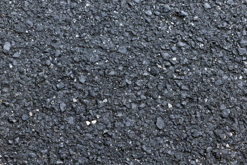 Close-up flat lay of rough asphalt pavement surface filling frame