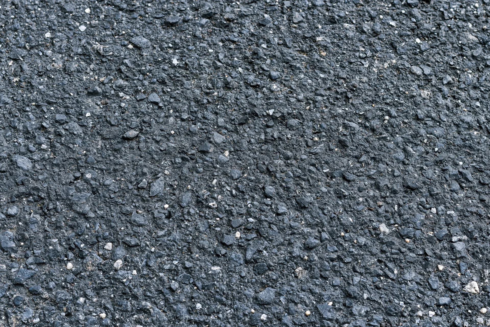 Close-up flat lay of rough asphalt pavement surface filling frame