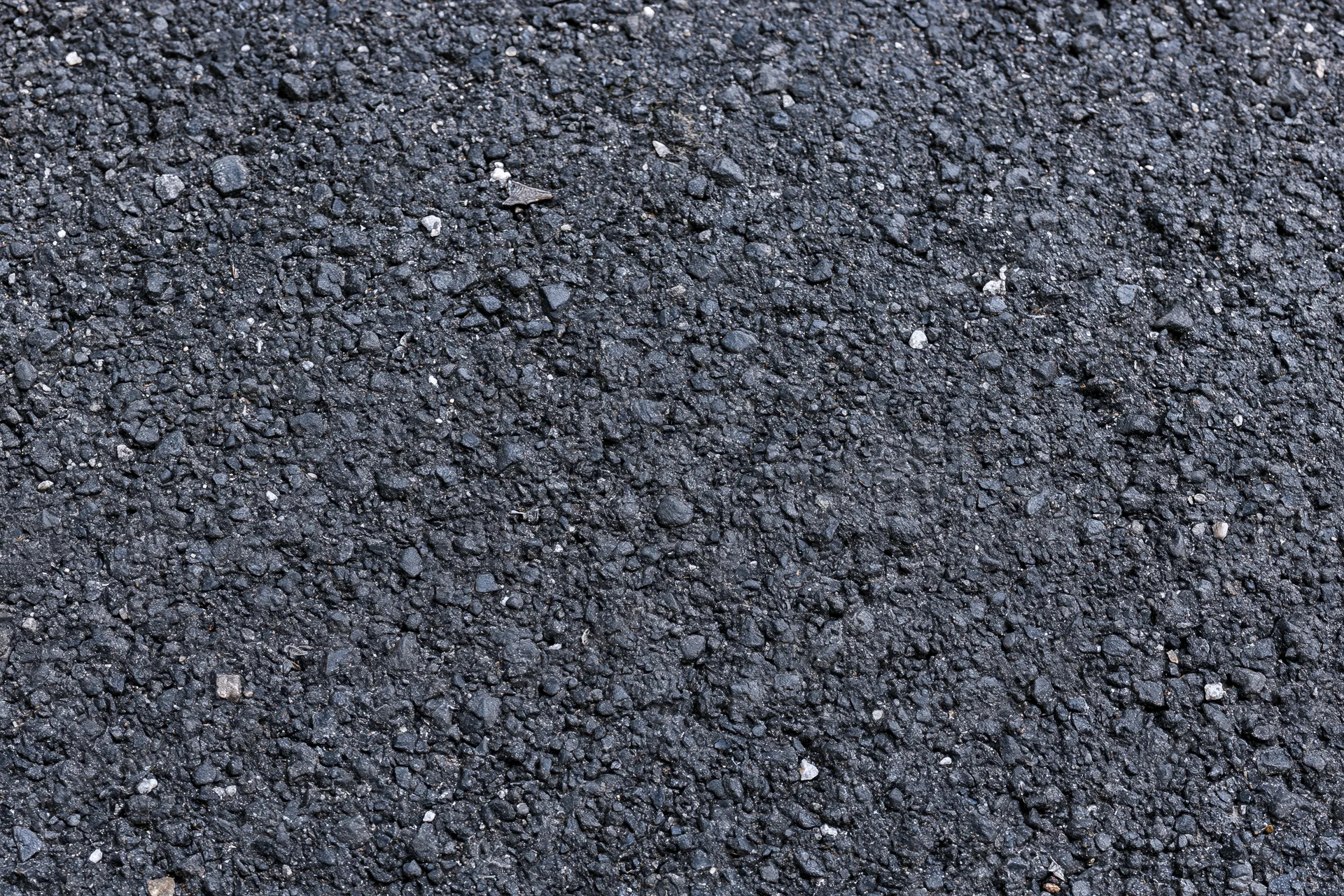 Close-up flat lay of rough asphalt pavement surface filling frame