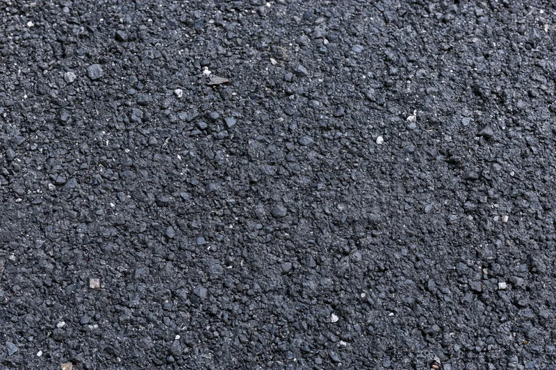 Close-up flat lay of rough asphalt pavement surface filling frame