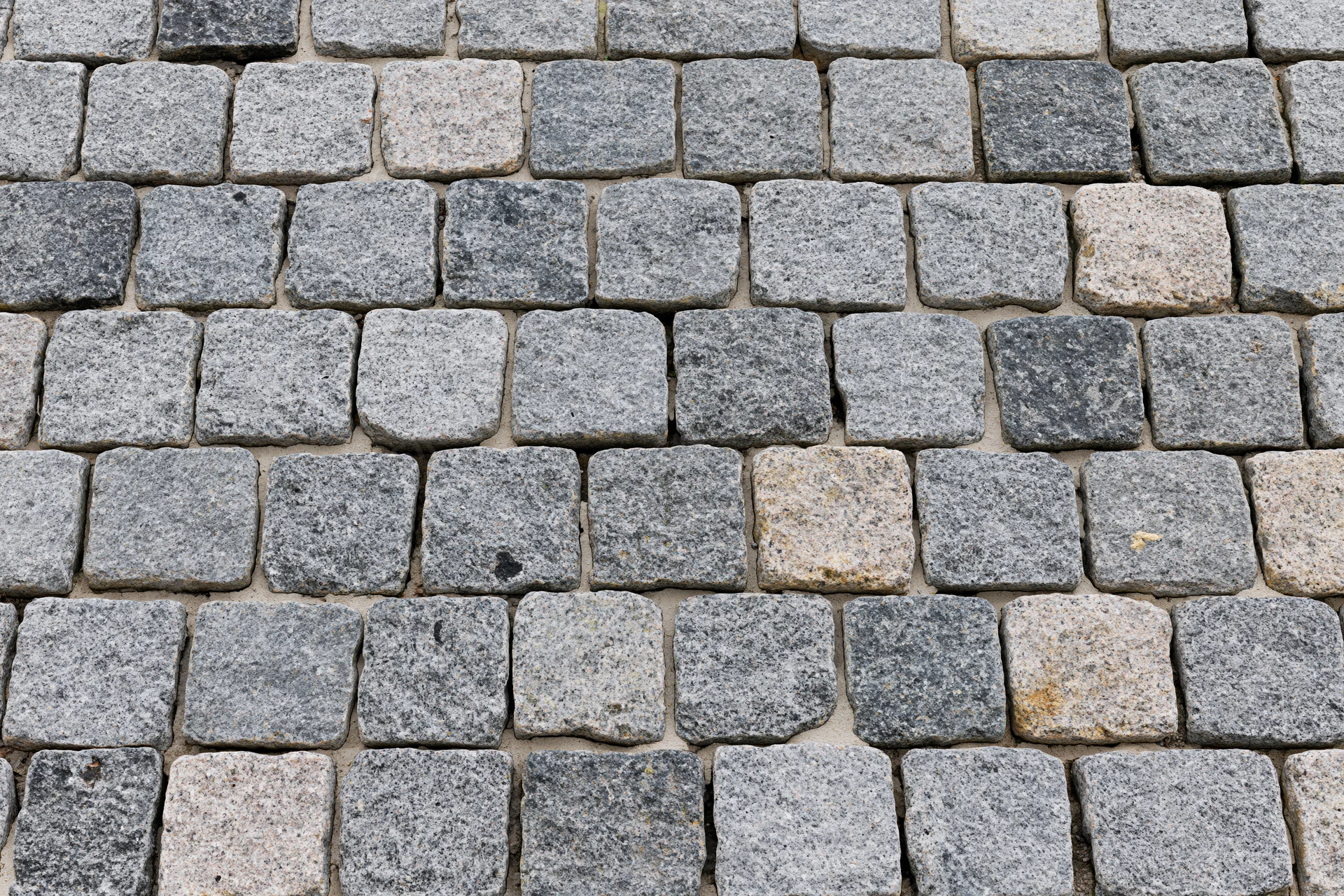 Close-up overhead view of gray cobblestone pavement arranged in a grid pattern