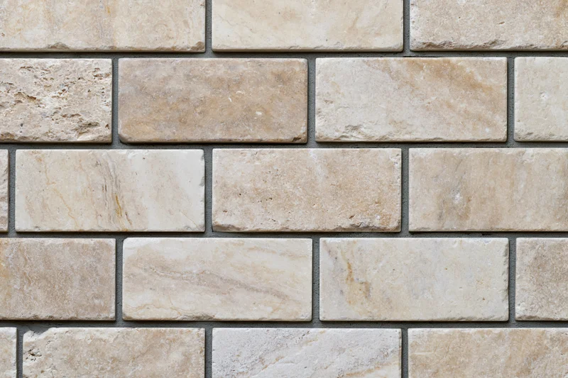 Close-up flat shot of rectangular travertine stone tiles in staggered pattern on wall