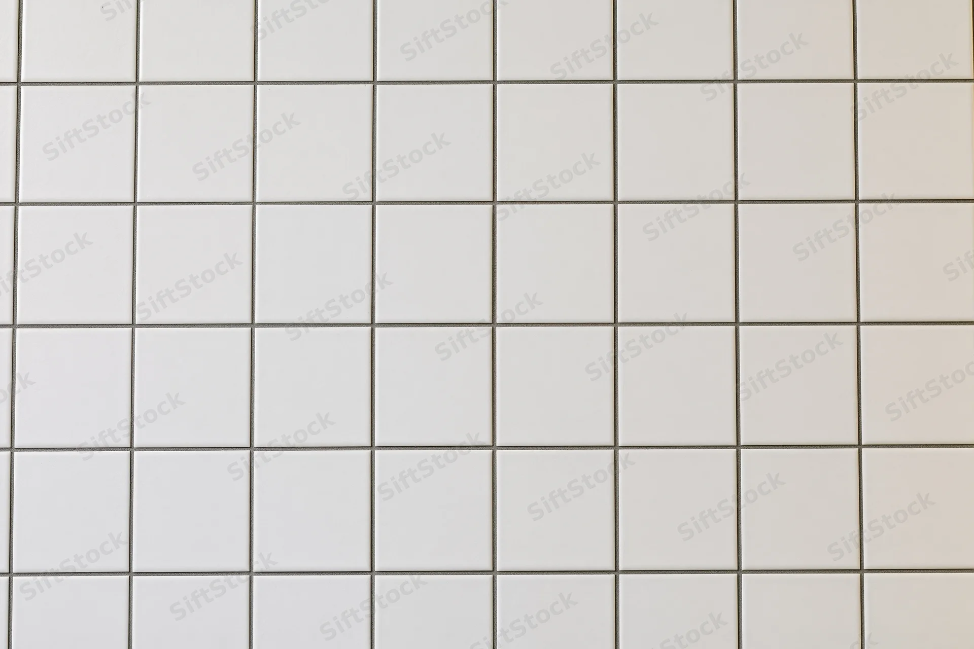 White ceramic tile wall arranged in a grid pattern covering the surface