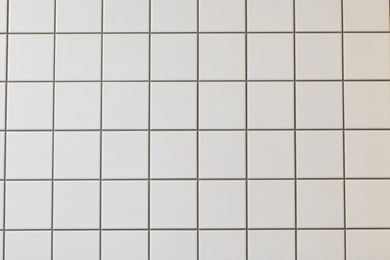 White ceramic tile wall arranged in a grid pattern covering the surface