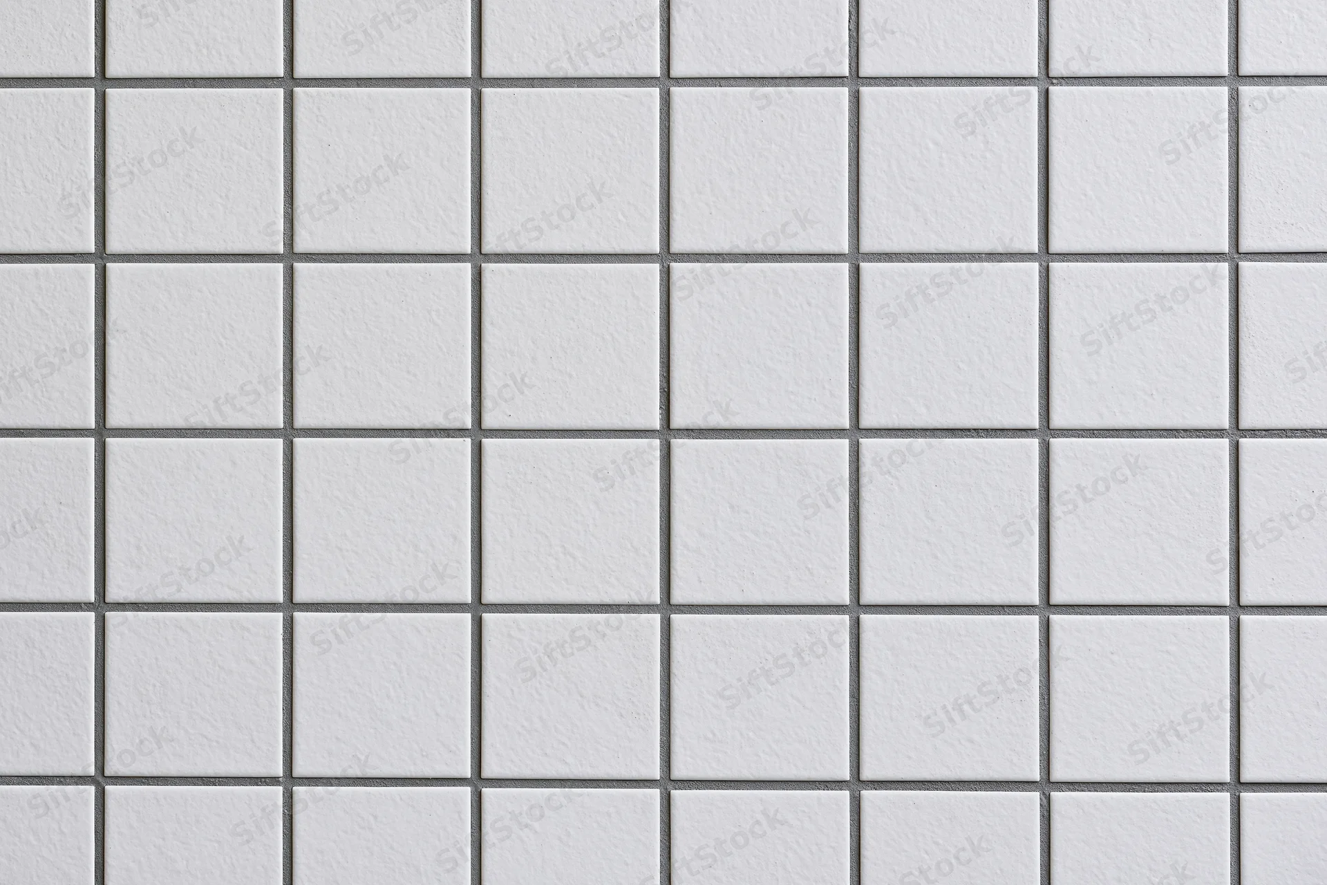 White ceramic tiles arranged in a grid pattern on a wall surface