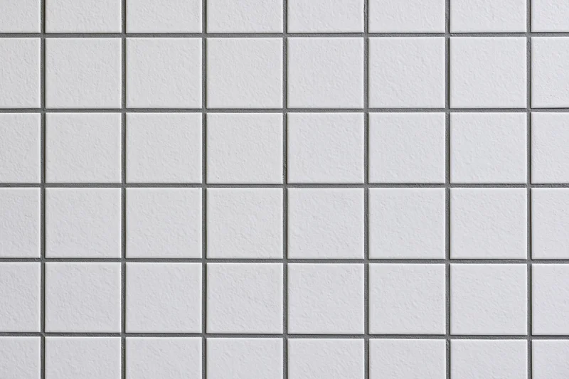 White ceramic tiles arranged in a grid pattern on a wall surface