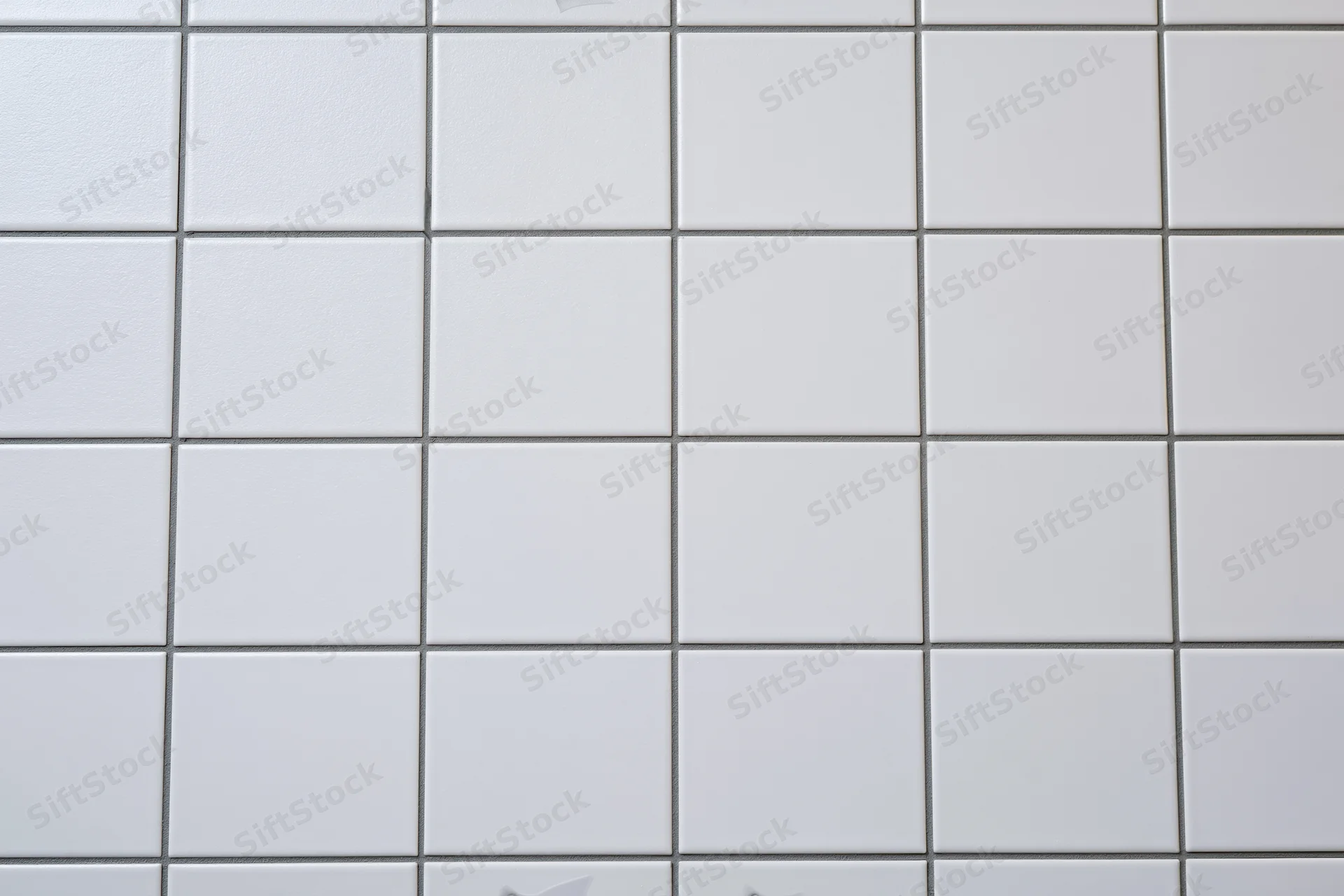 White ceramic tiles arranged in a grid pattern on a wall