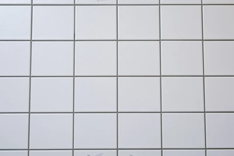 White ceramic tiles arranged in a grid pattern on a wall