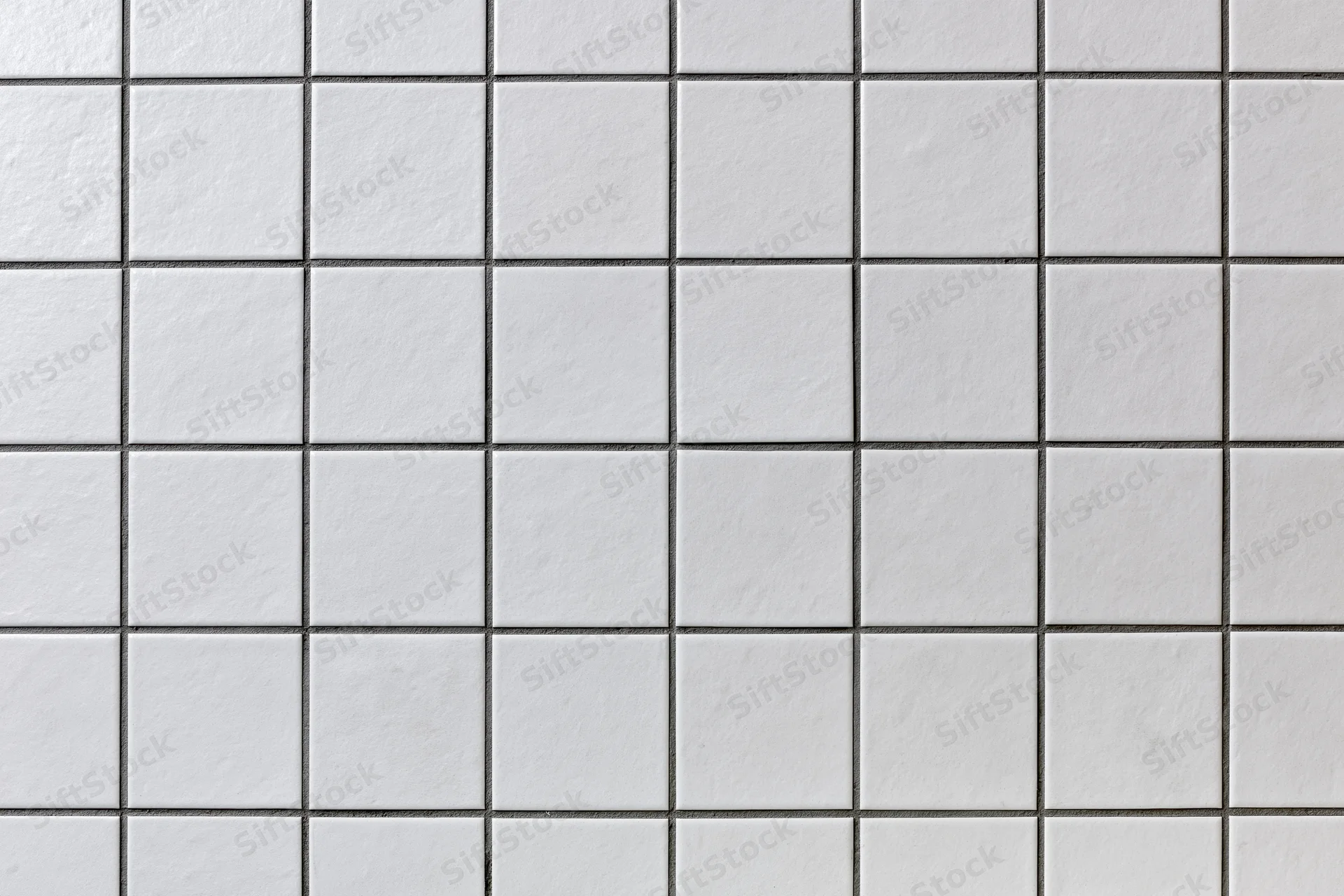 White ceramic tiles arranged in a grid pattern on a wall