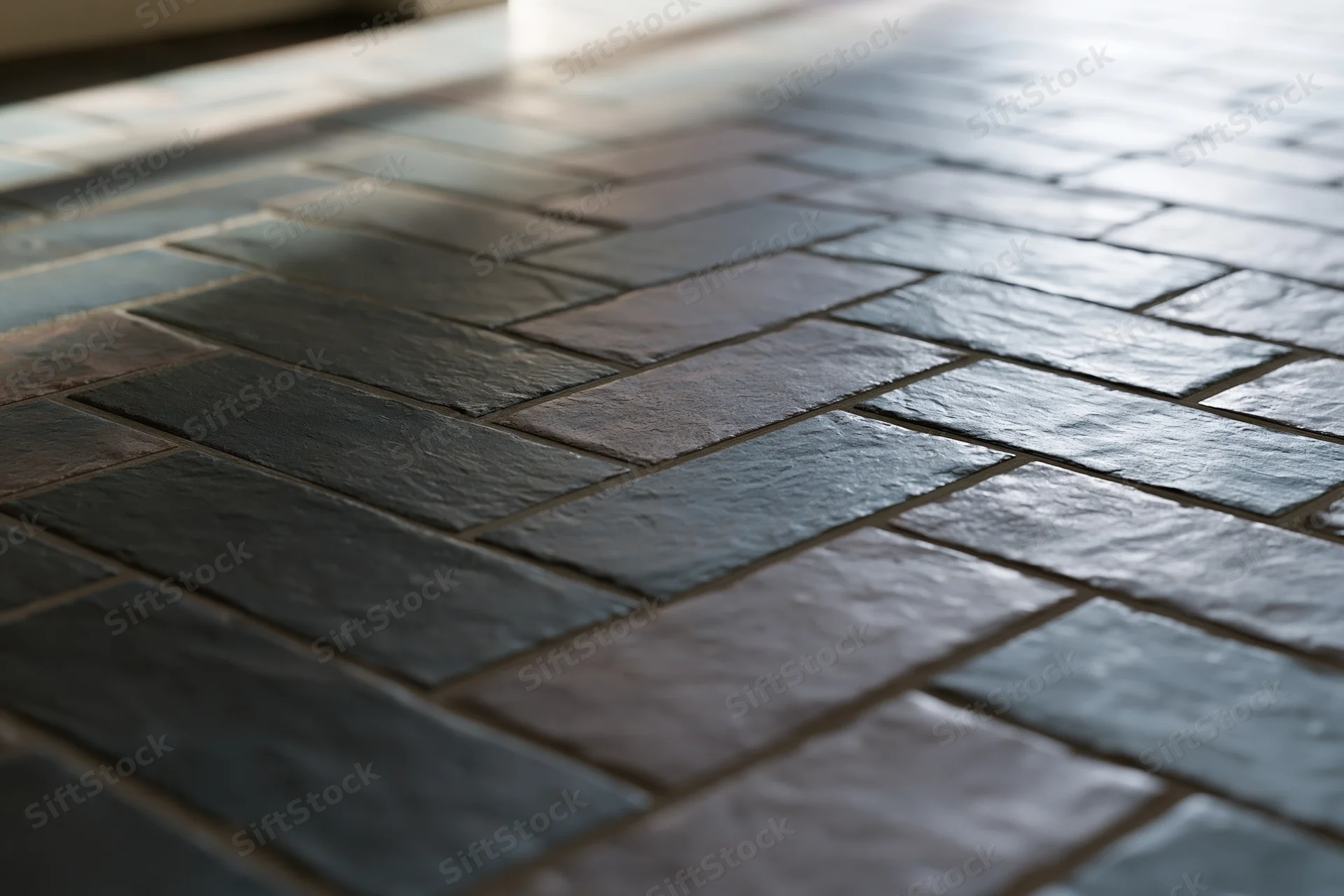 Dark slate tiles arranged in herringbone pattern on outdoor floor surface