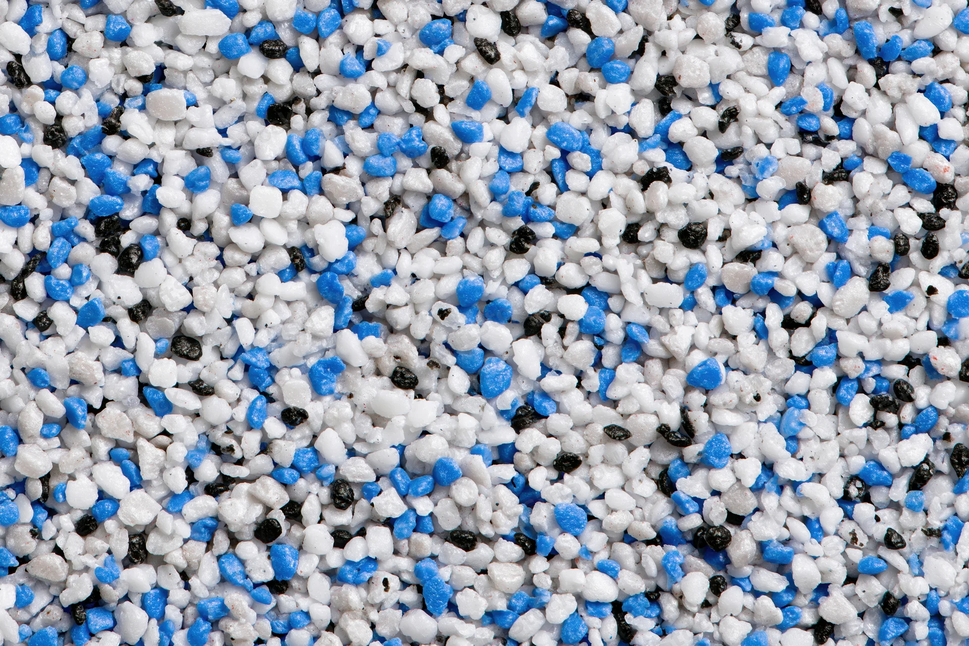 Close-up of mixed plastic polymer granules scattered across a flat surface