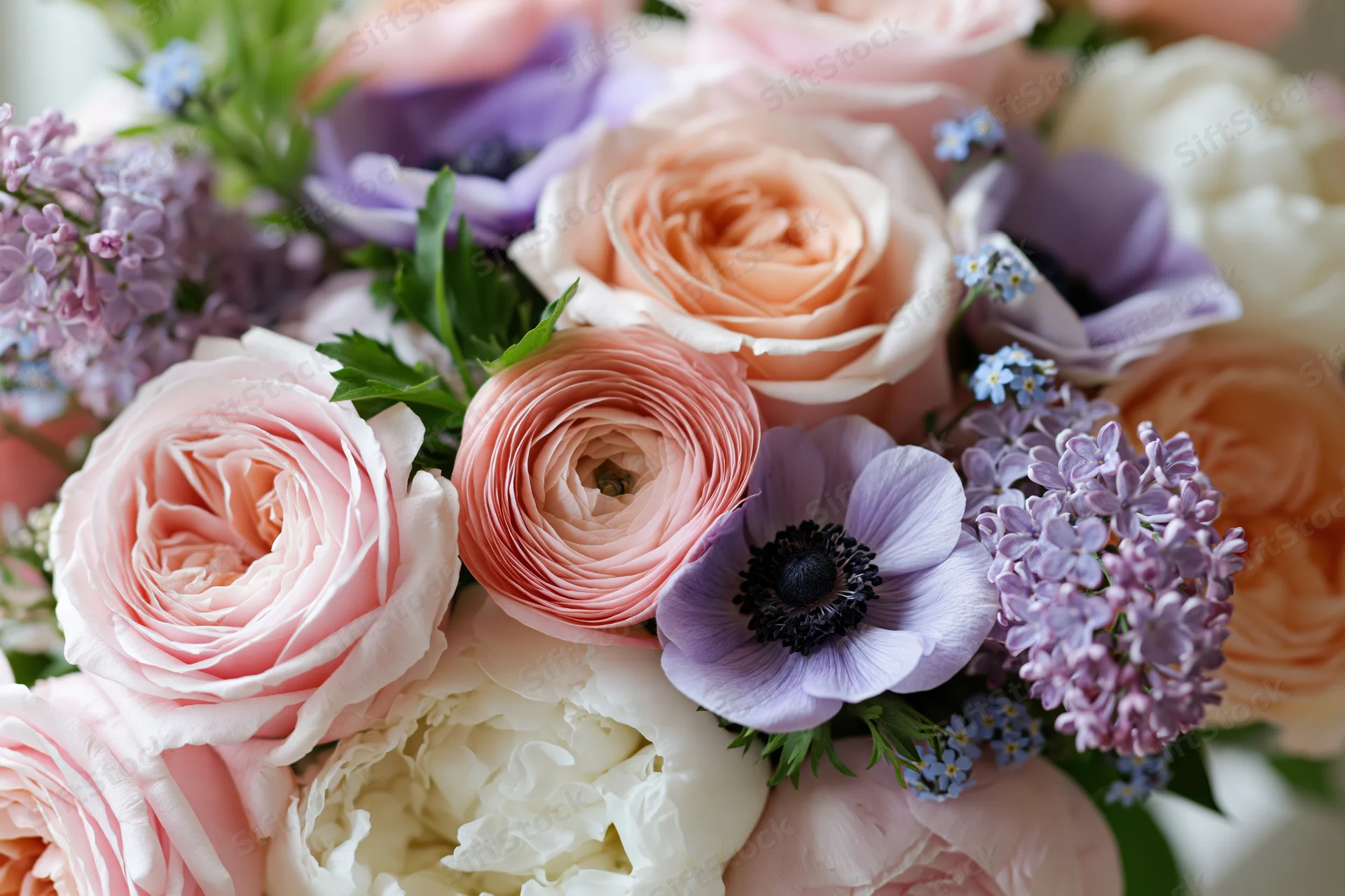 Close-up of a mixed floral arrangement with pink roses, purple anemones, lilac, and white peonies in soft pastel tones