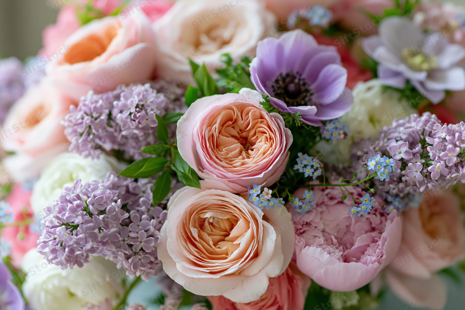 Close-up of a mixed floral arrangement with garden roses, peonies, lilacs and anemones in soft pastel tones
