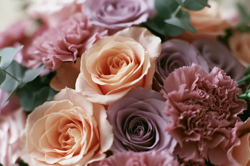 Close-up of a mixed floral bouquet with peach roses and pink carnations arranged with eucalyptus greenery