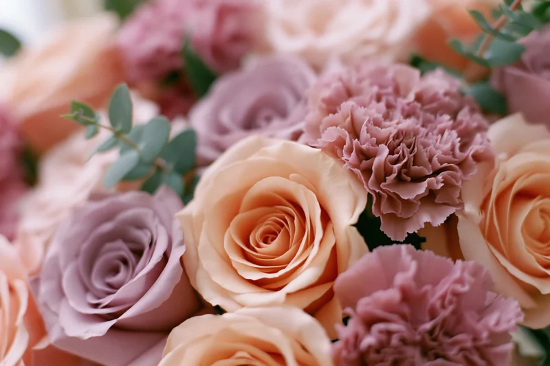 Close-up of a mixed floral bouquet with peach roses and pink carnations accented by eucalyptus leaves