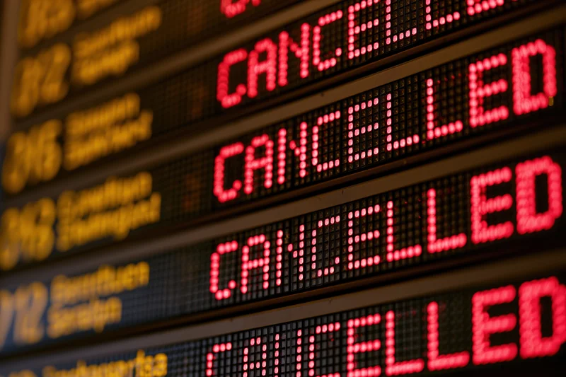 Close-up of airport departure board showing multiple cancelled flights in red led text