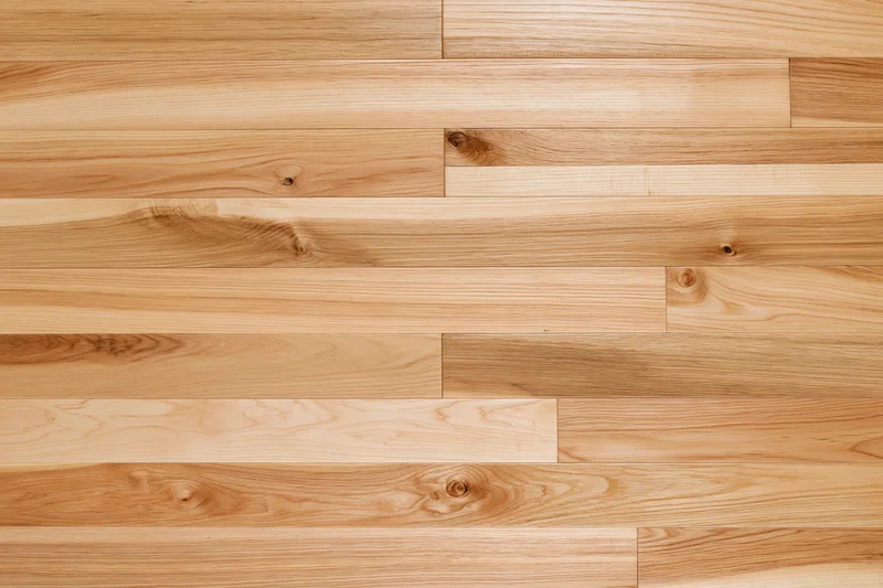 Light hardwood parquet flooring arranged in horizontal planks with visible wood grain and knots, viewed from overhead flat lay perspective