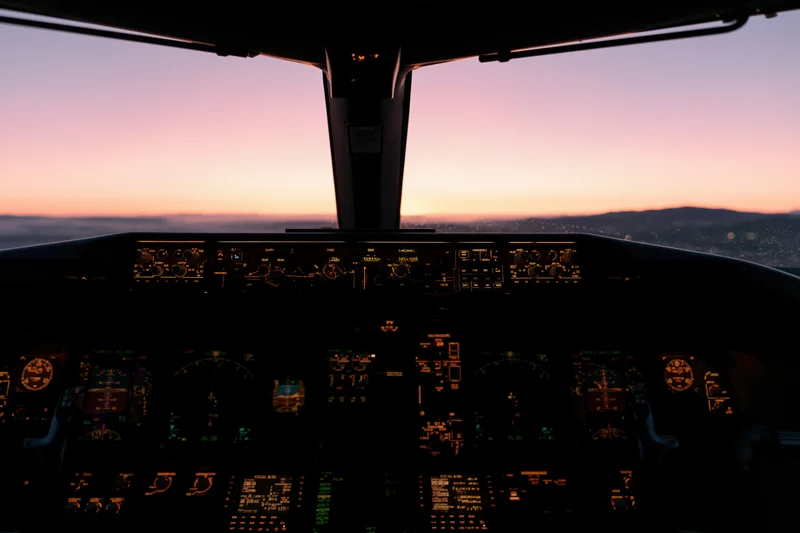 Cockpit interior of a commercial airliner at sunrise showing illuminated flight instruments and a view of the horizon over mountains and city
