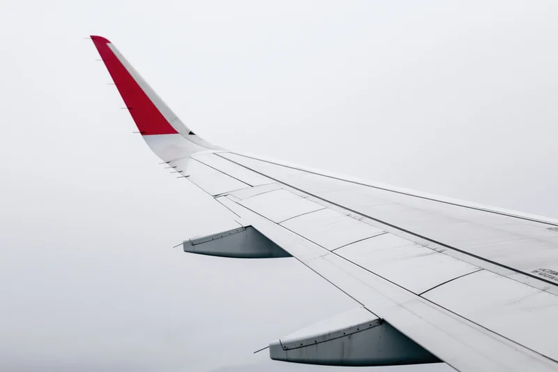 Commercial airplane wing viewed from passenger window during flight in overcast sky