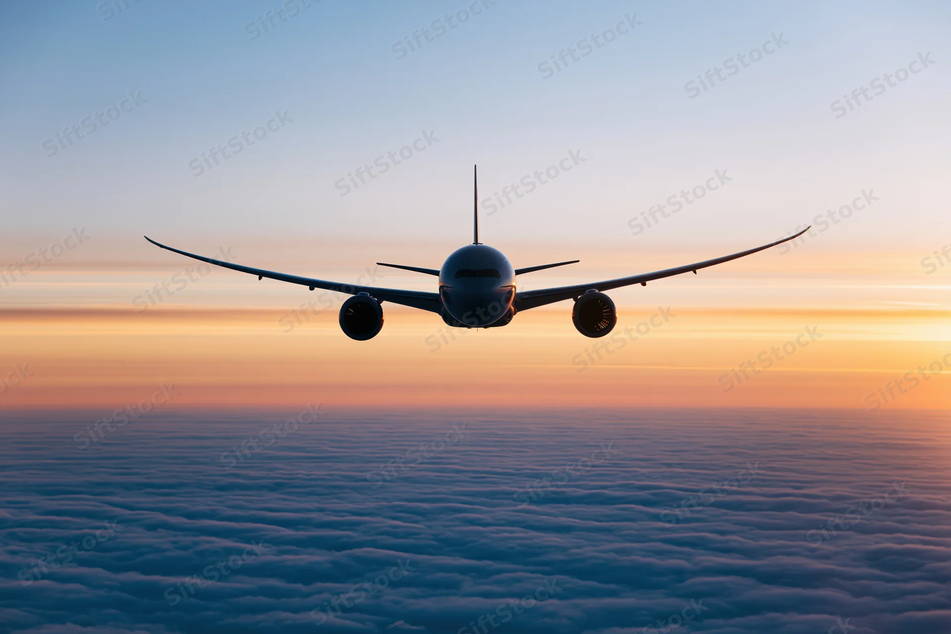 Commercial passenger jet flying above dense cloud layer at sunset