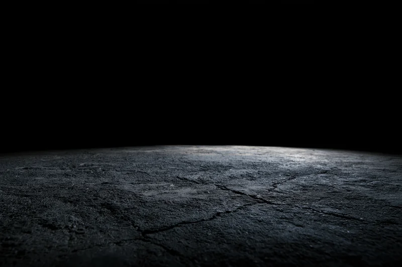 Cracked concrete floor fading into darkness from low angle wide view