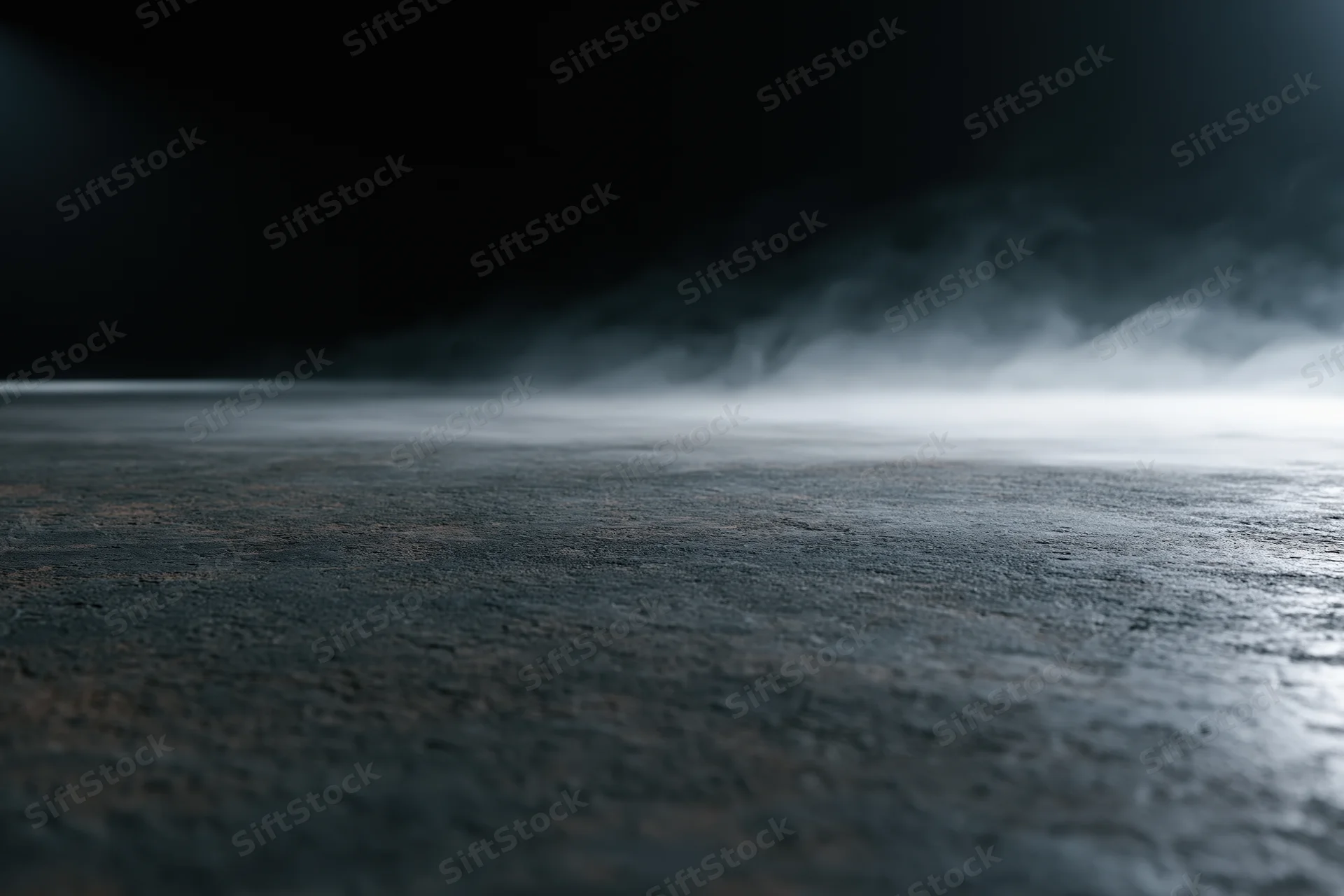 Dark empty concrete floor with low-lying smoke drifting across the surface