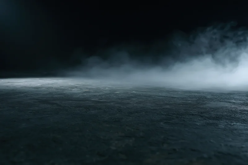 Dark empty concrete floor with low-lying smoke drifting across the surface