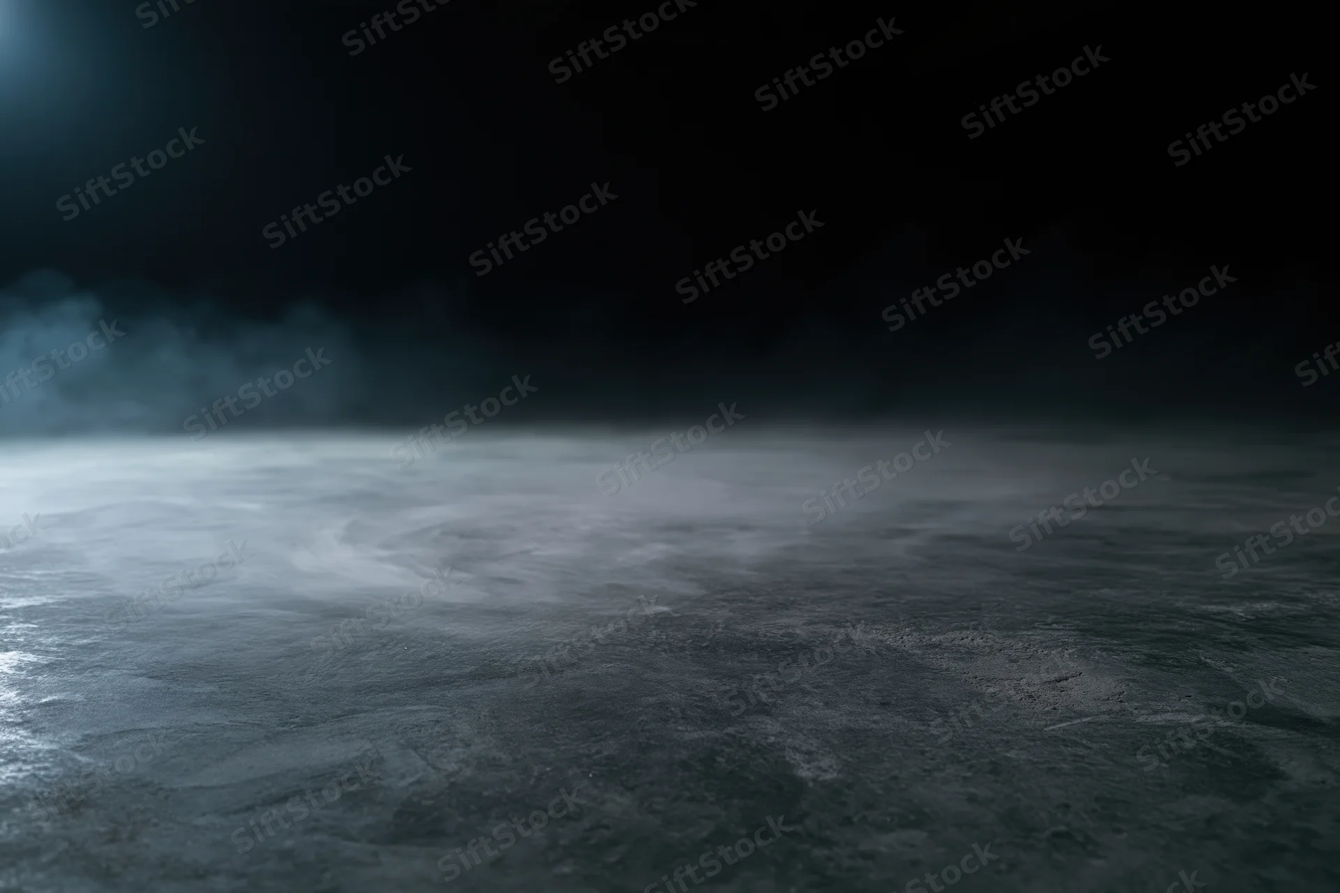 Dark empty concrete floor with low-lying smoke drifting across the surface