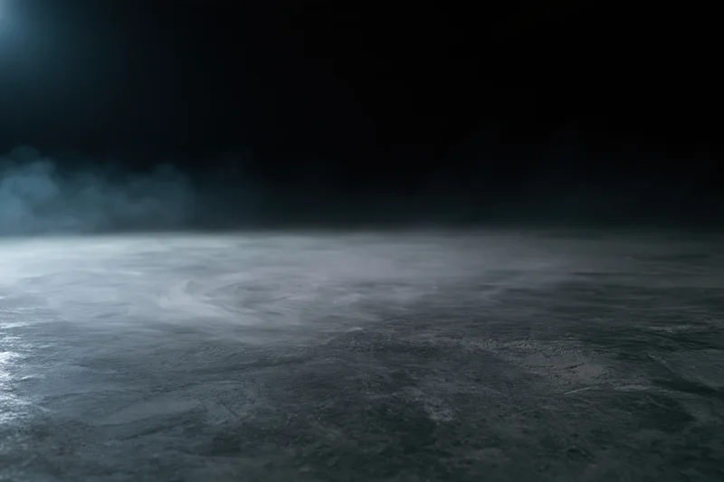 Dark empty concrete floor with low-lying smoke drifting across the surface