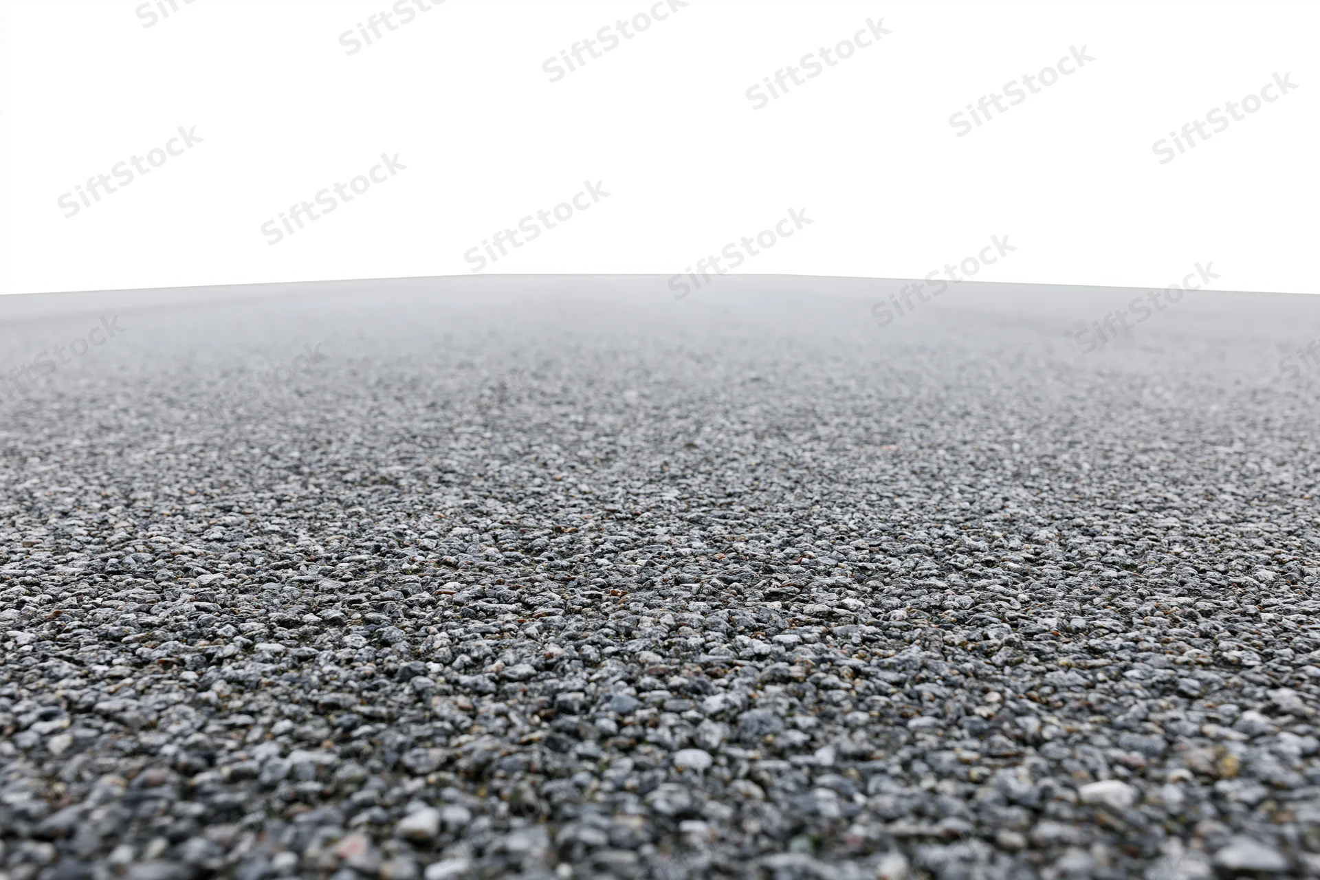 Asphalt road surface filling lower half of frame with gravel texture and white sky above