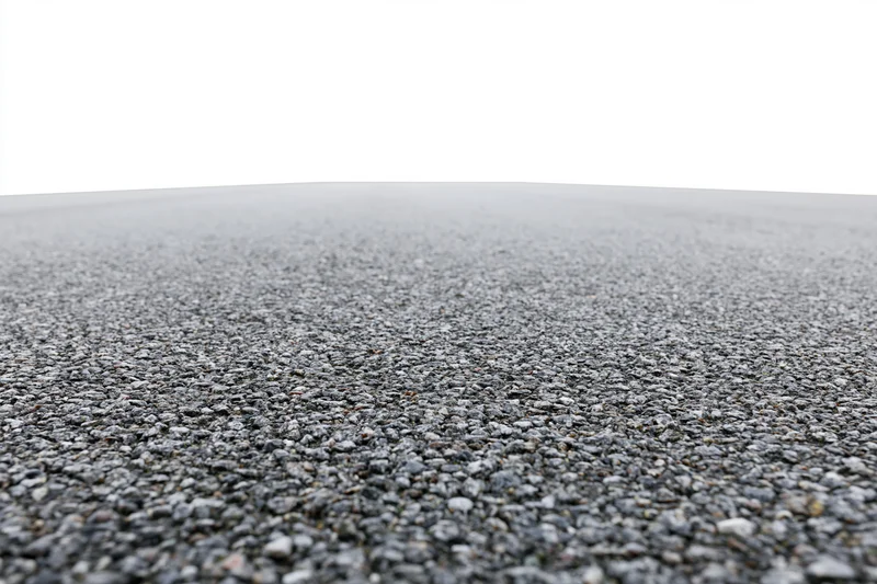 Asphalt road surface filling lower half of frame with gravel texture and white sky above