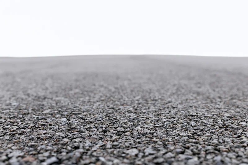 Asphalt road surface filling lower half of frame with white sky above