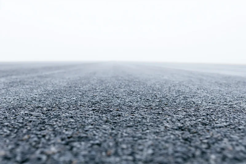 Asphalt road surface filling lower half of frame with shallow depth of field and vanishing point in distance