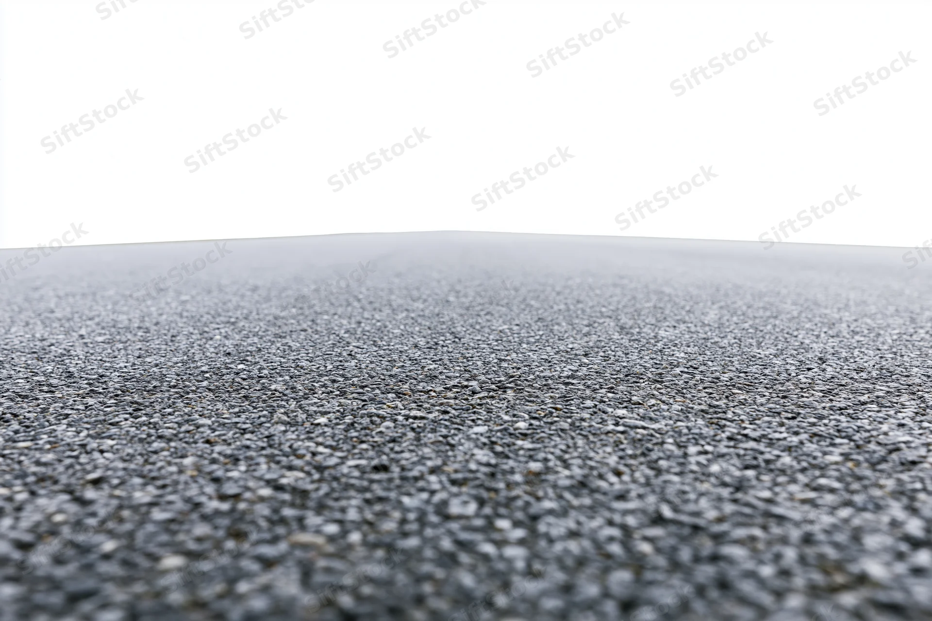 Asphalt road surface filling lower half of frame with textured pavement and white sky above