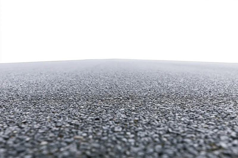 Asphalt road surface filling lower half of frame with textured pavement and white sky above
