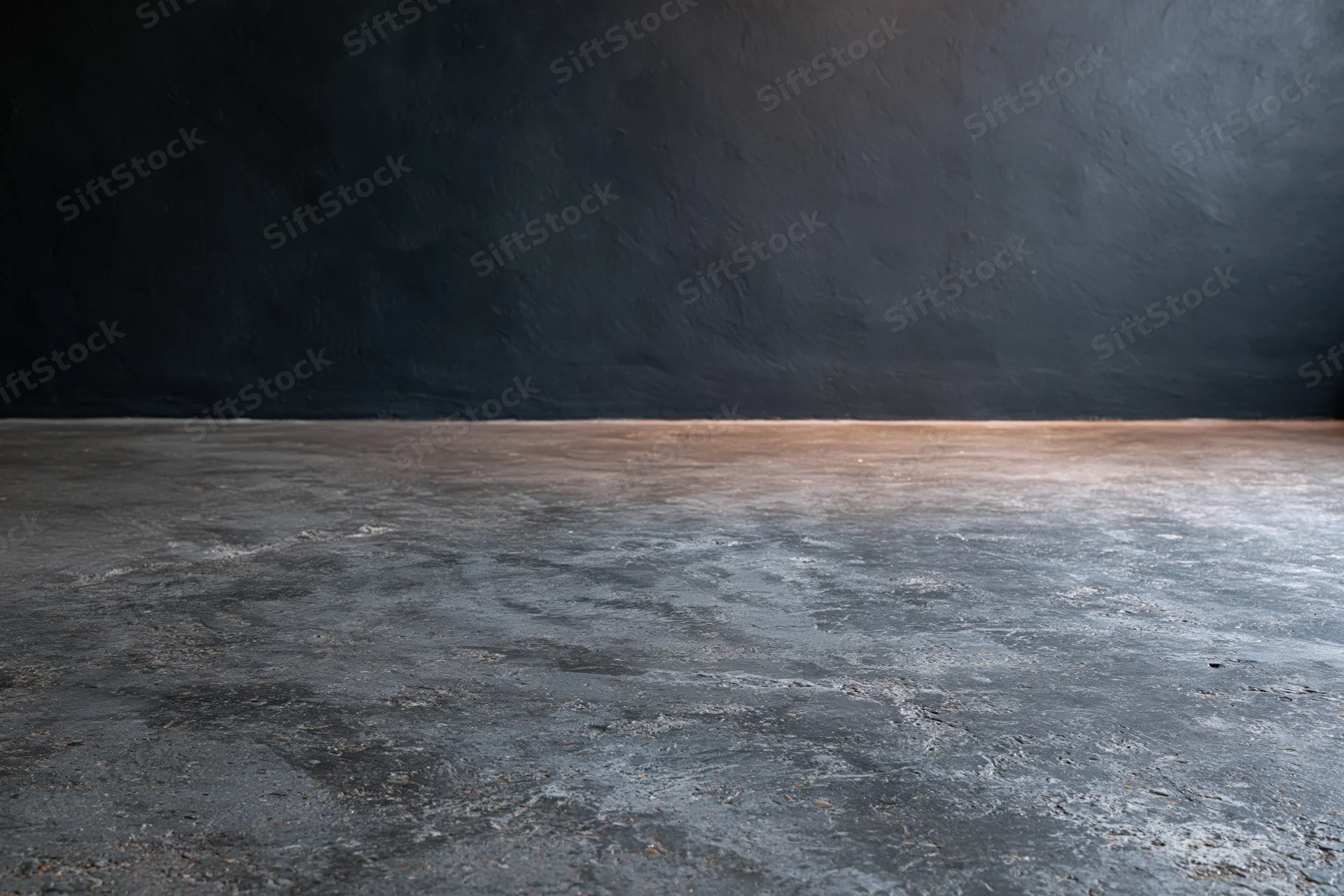 Empty concrete floor meeting dark bare plaster wall in industrial interior space