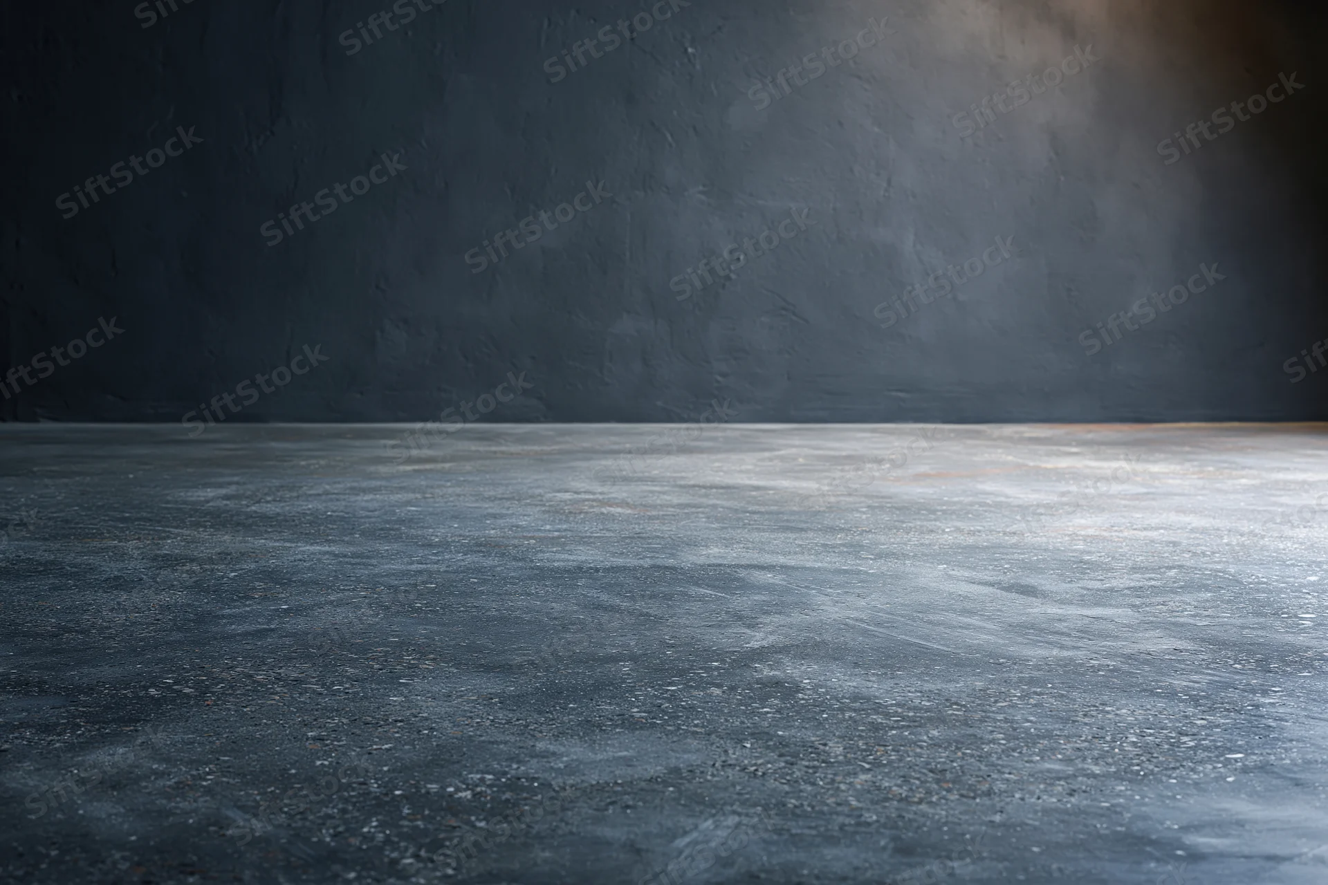 Empty concrete floor meeting dark bare plaster wall in industrial interior space