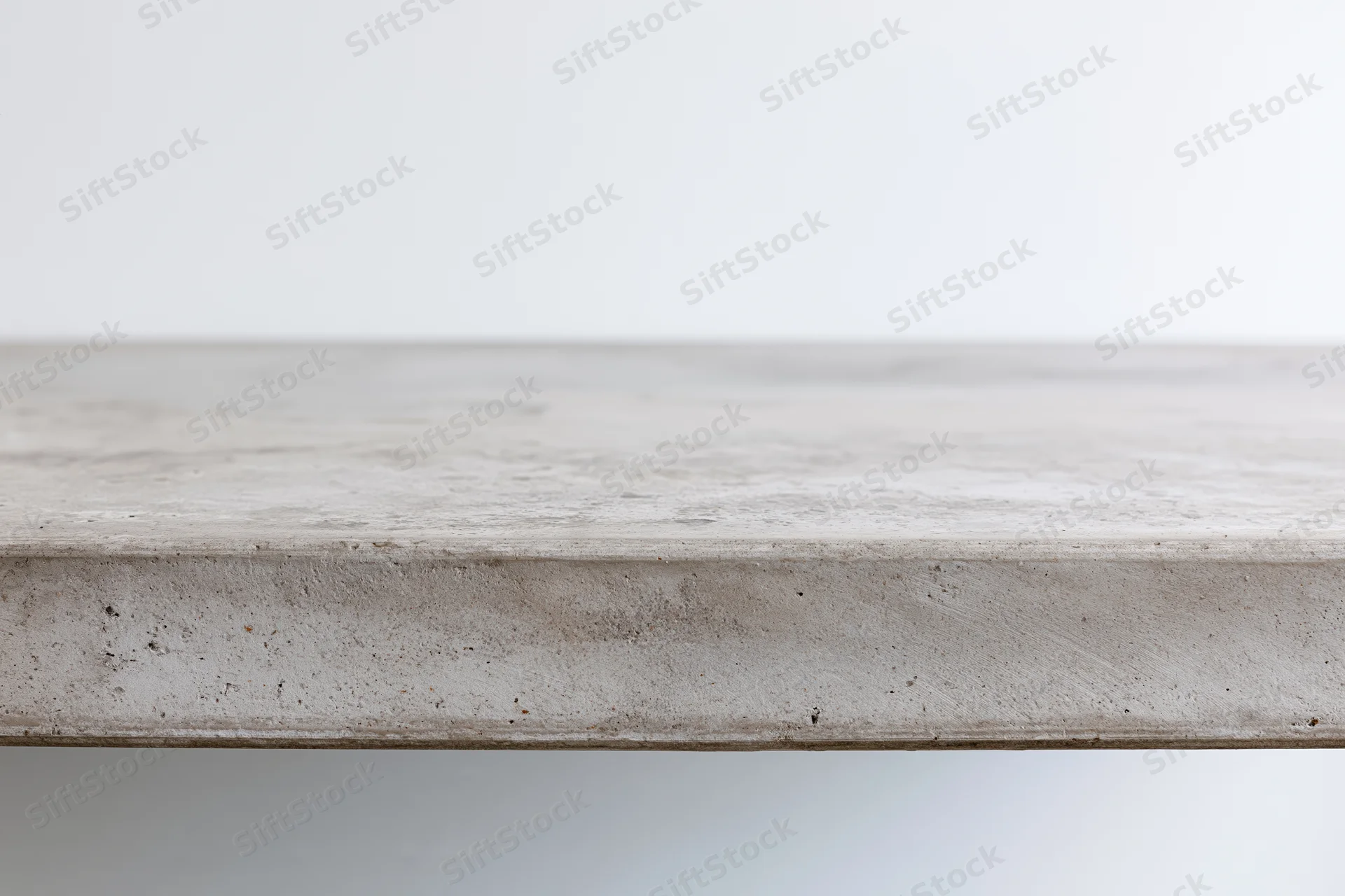 Empty concrete tabletop viewed straight on from low angle with horizontal edge and textured surface