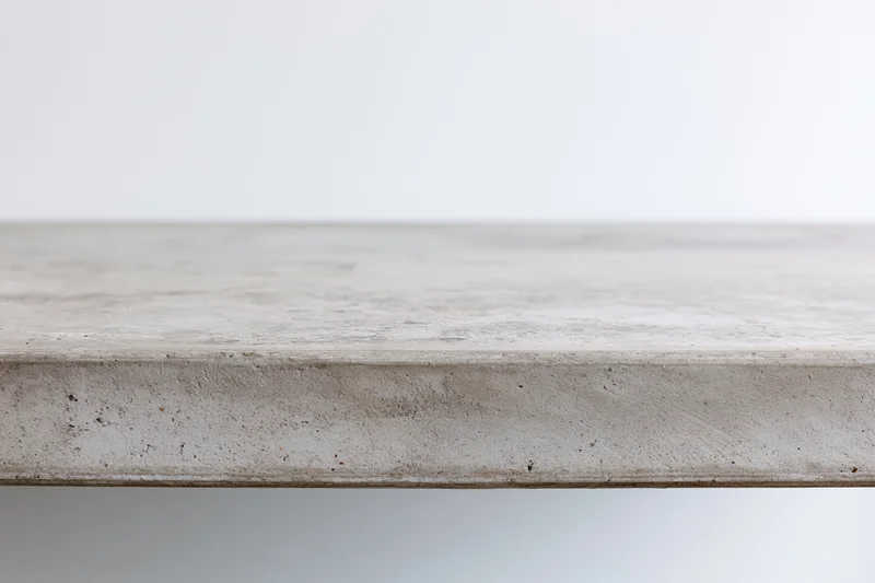Empty concrete tabletop viewed straight on from low angle with horizontal edge and textured surface