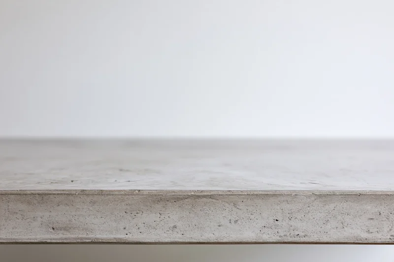 Empty concrete tabletop viewed straight on from low angle with clean edge and neutral surface