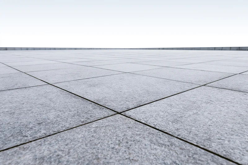 Concrete tile plaza floor stretching to white horizon in low-angle wide view