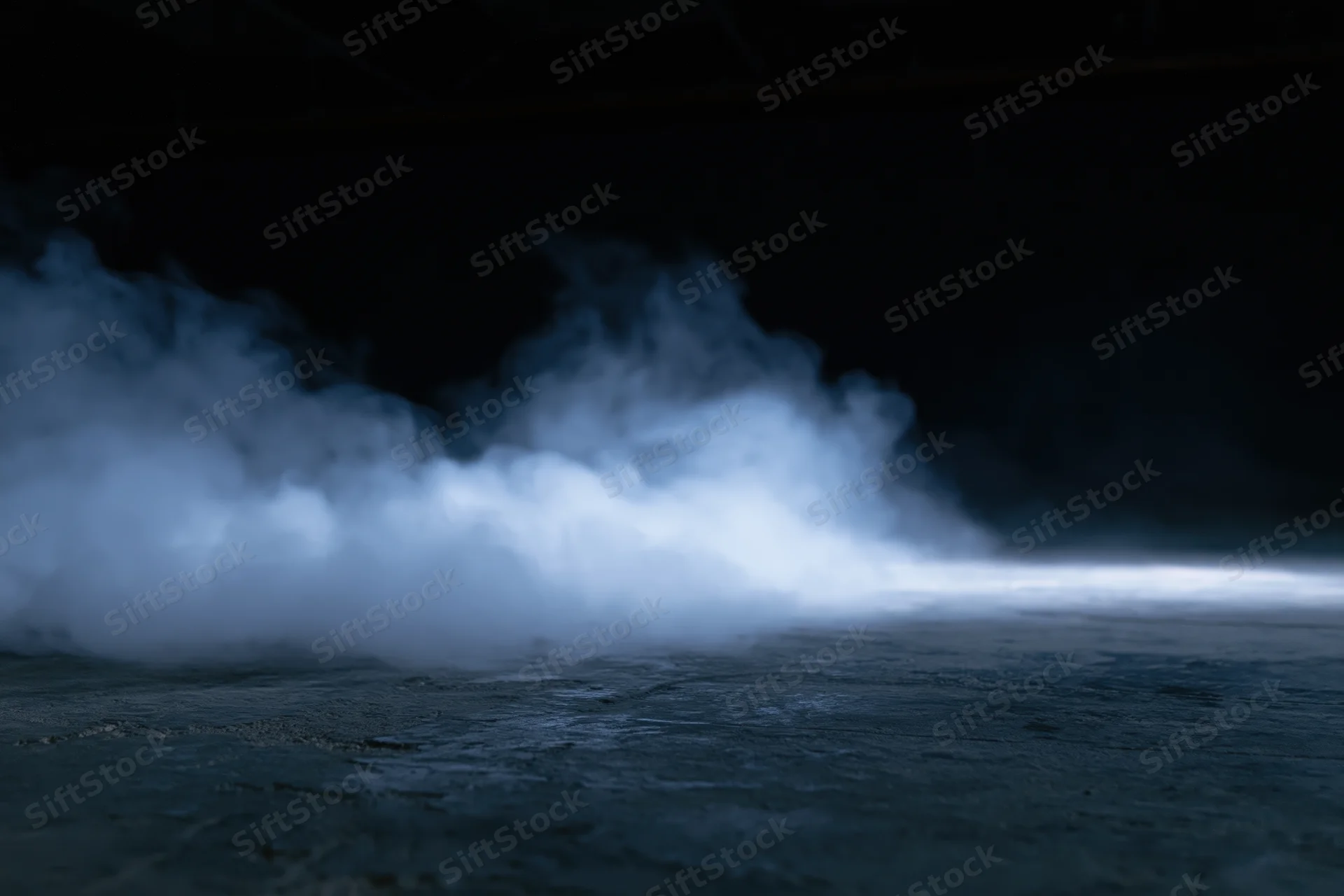 Thick white smoke drifting across dark concrete floor in industrial space